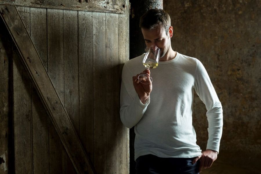 Weingut Lohr Frank Lohr richt an Weinglas vor Holztür